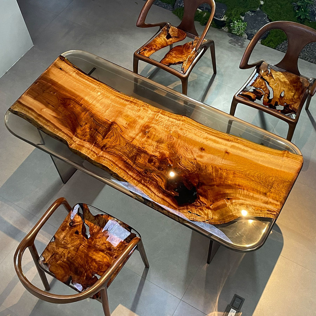 A resin - topped wooden table with a natural live - edge design, accompanied by matching chairs.