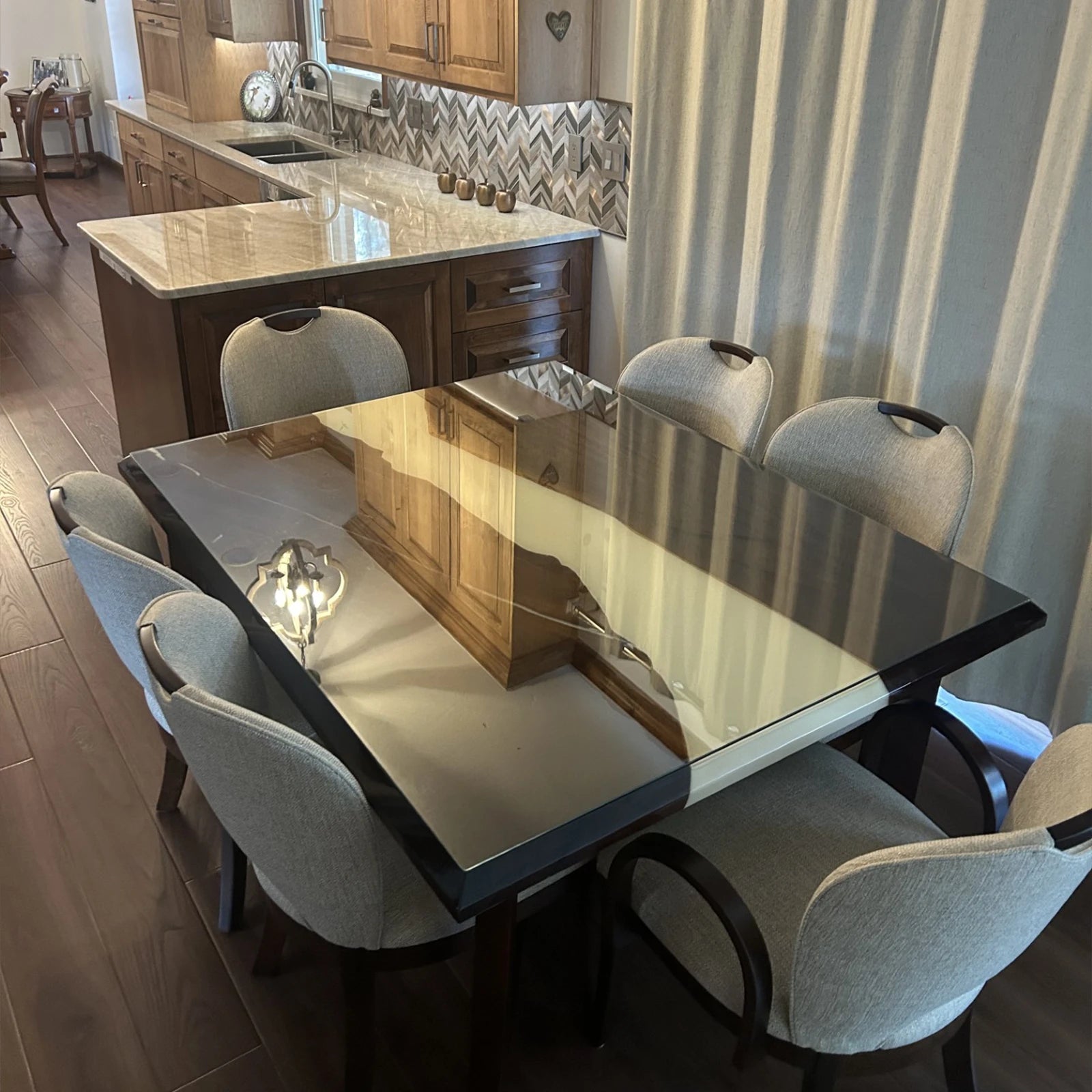 Glossy black resin dining table reflecting kitchen cabinetry in a modern open-concept space