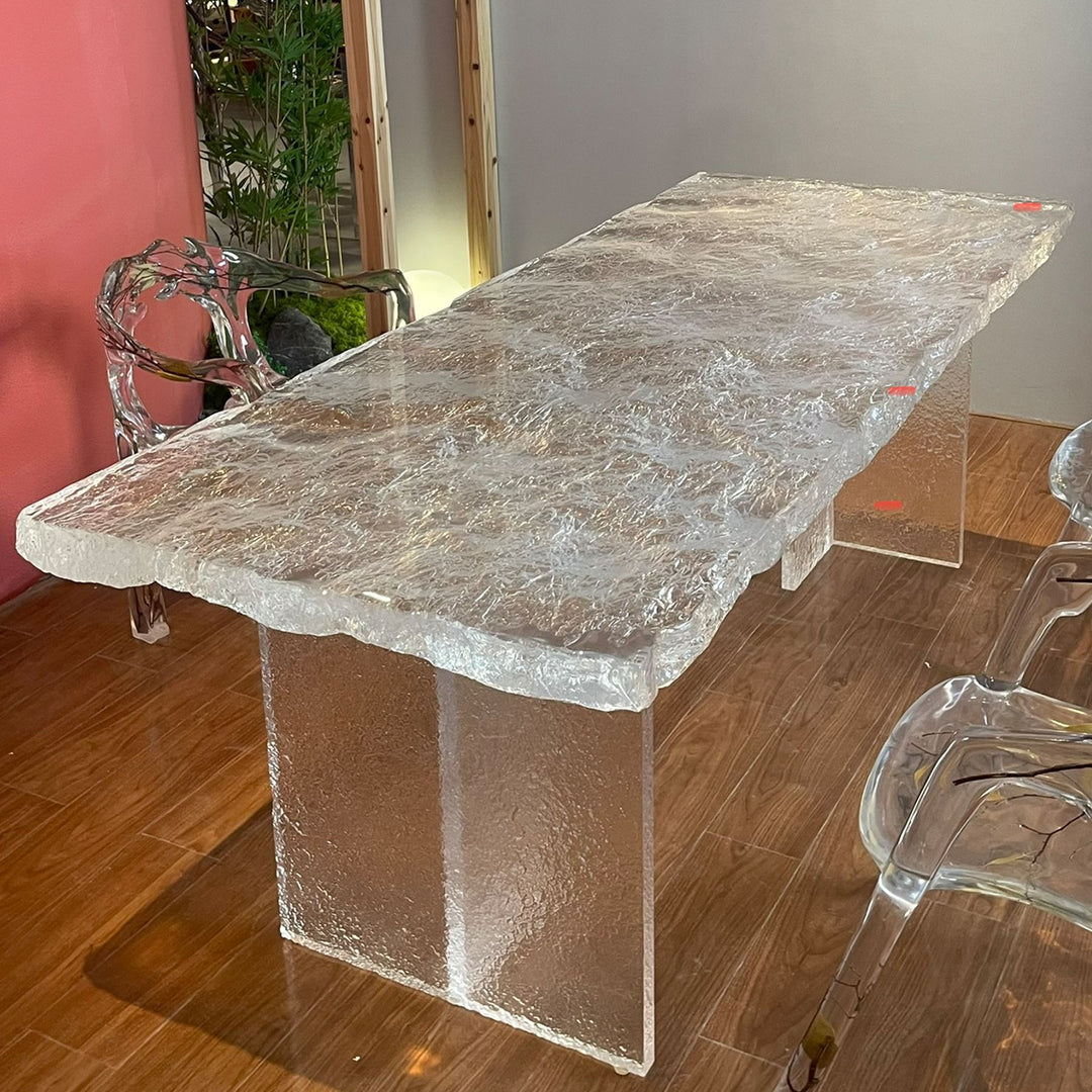 A contemporary resin dining table with a textured surface and clear resin legs.