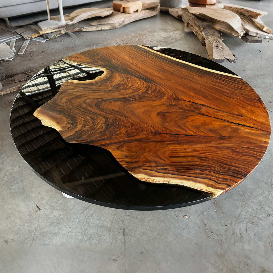 Round wooden table with black base on a concrete floor
