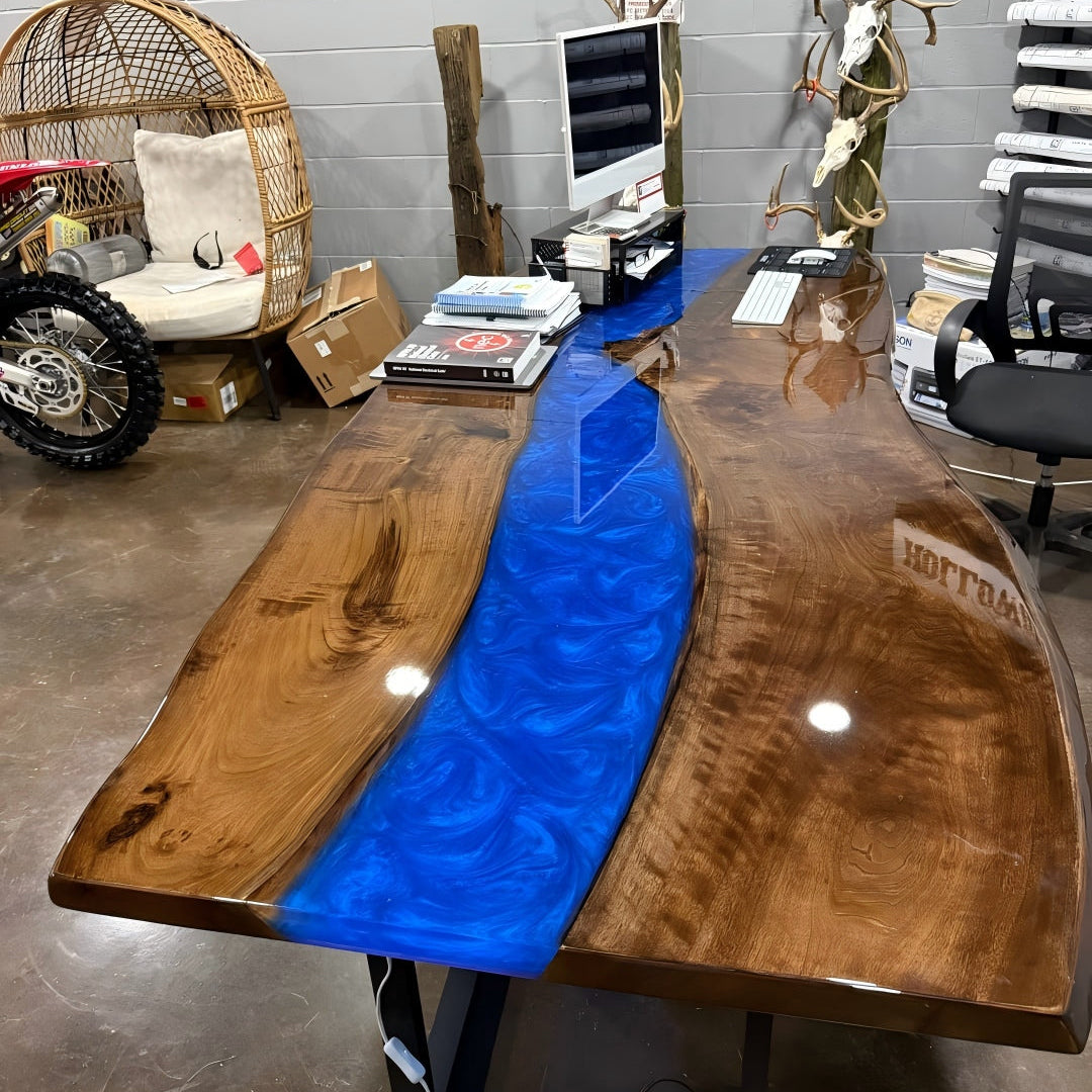 Ocean-inspired epoxy river table illuminated by LED lights at night, creating a luxurious deep-sea glow across the glossy walnut surface.
