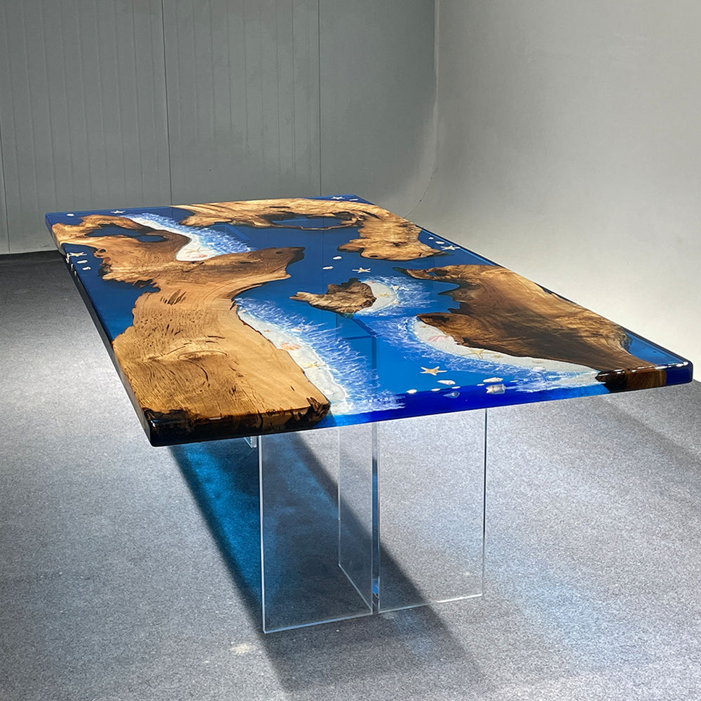 Dining table with wooden edge and blue resin finish on a gray floor.