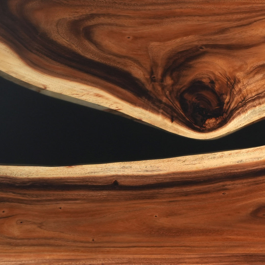 Surface detail of a custom epoxy table capturing the striking contrast between the warm walnut wood and the deep black glossy resin river - SeawaveTable