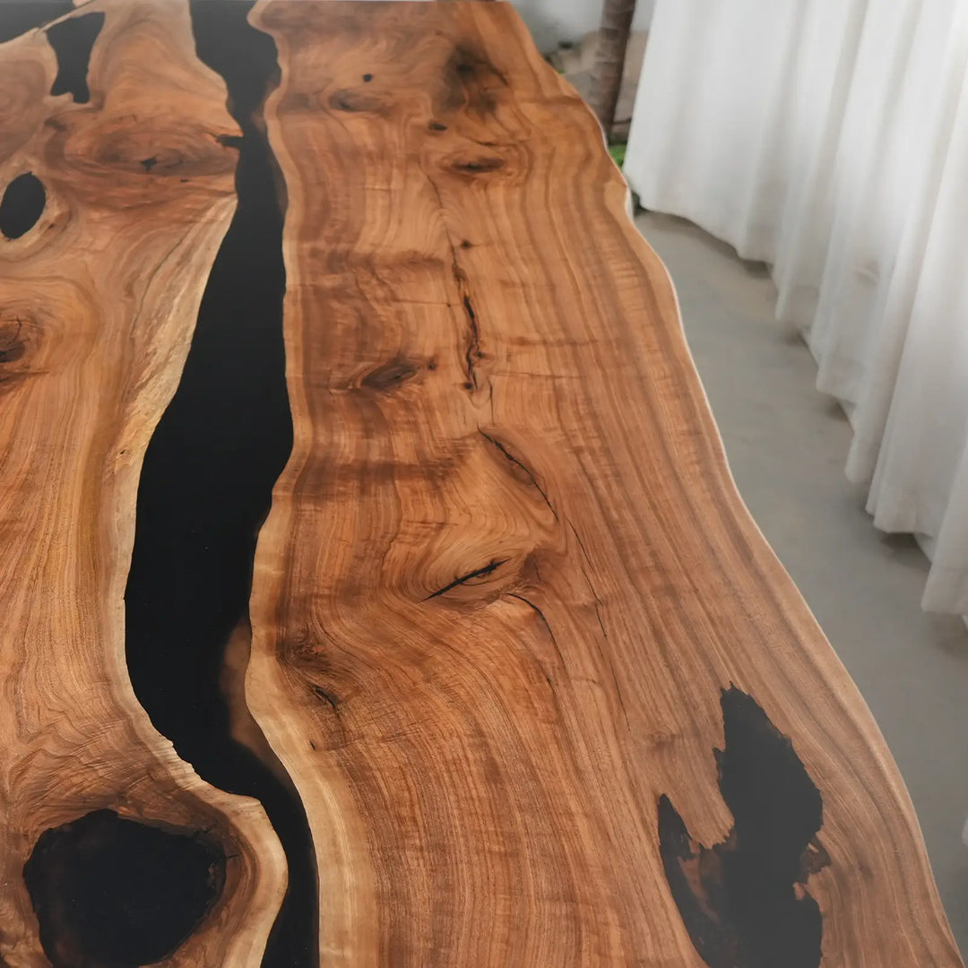 Rustic modern walnut dining table with irregular live edges and artistic black epoxy resin filling.