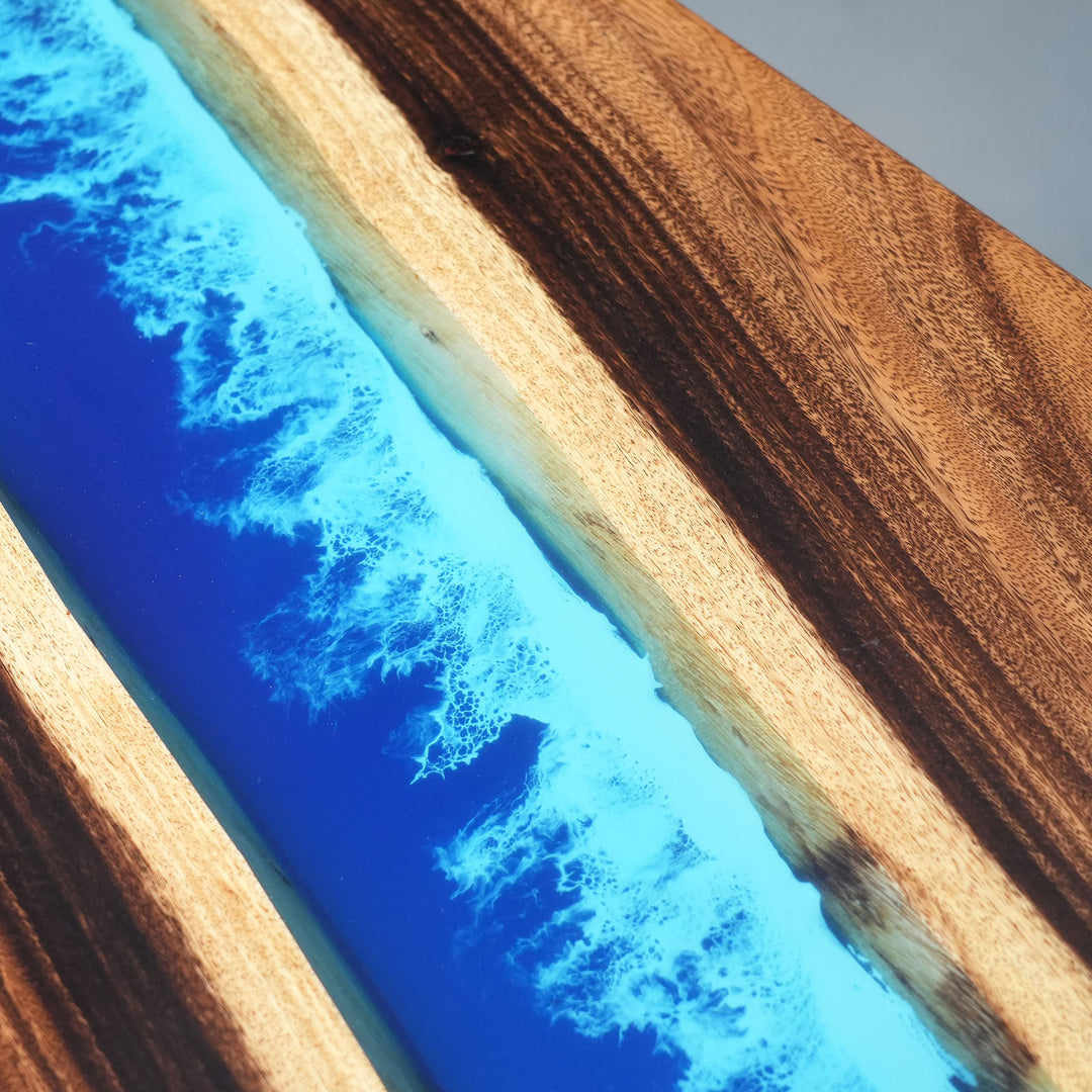 Artisanal woodworking: blue epoxy resin river table with natural wood crust.