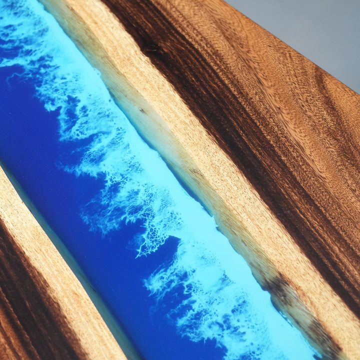 Artisanal woodworking: blue epoxy resin river table with natural wood crust.