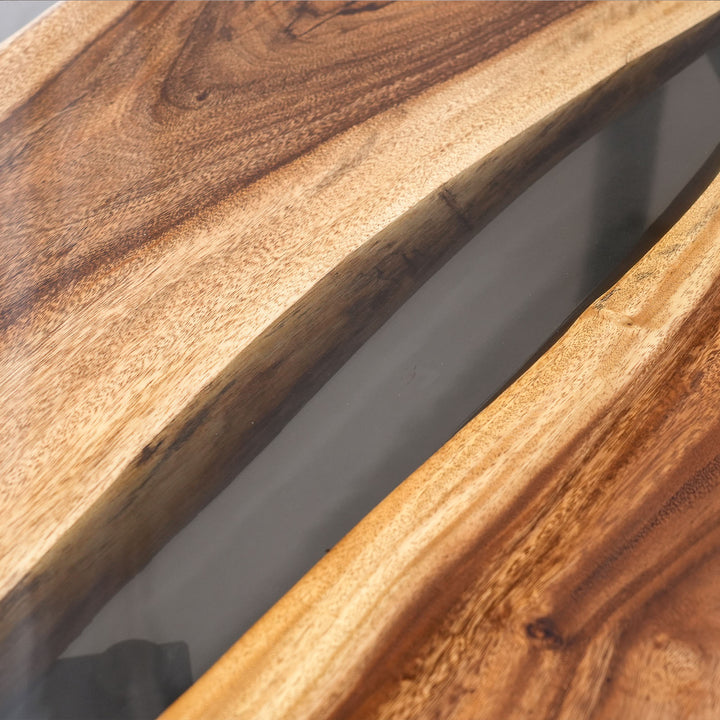 Close-up of premium walnut grain and smoky black epoxy resin river on a custom dining table.