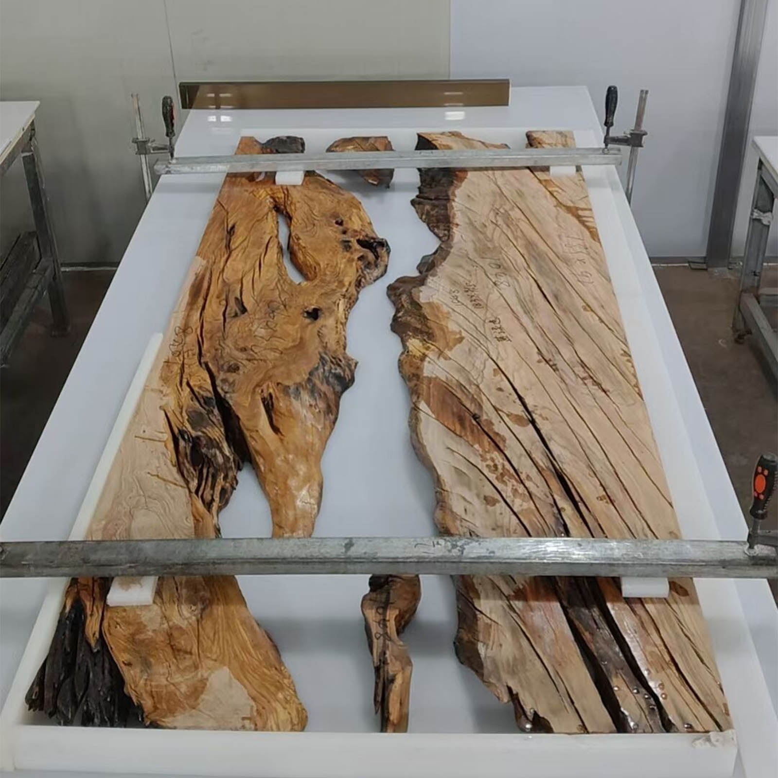 Solid olive wood river dining table with Mystic Lagoon resin in a modern dining room setting.