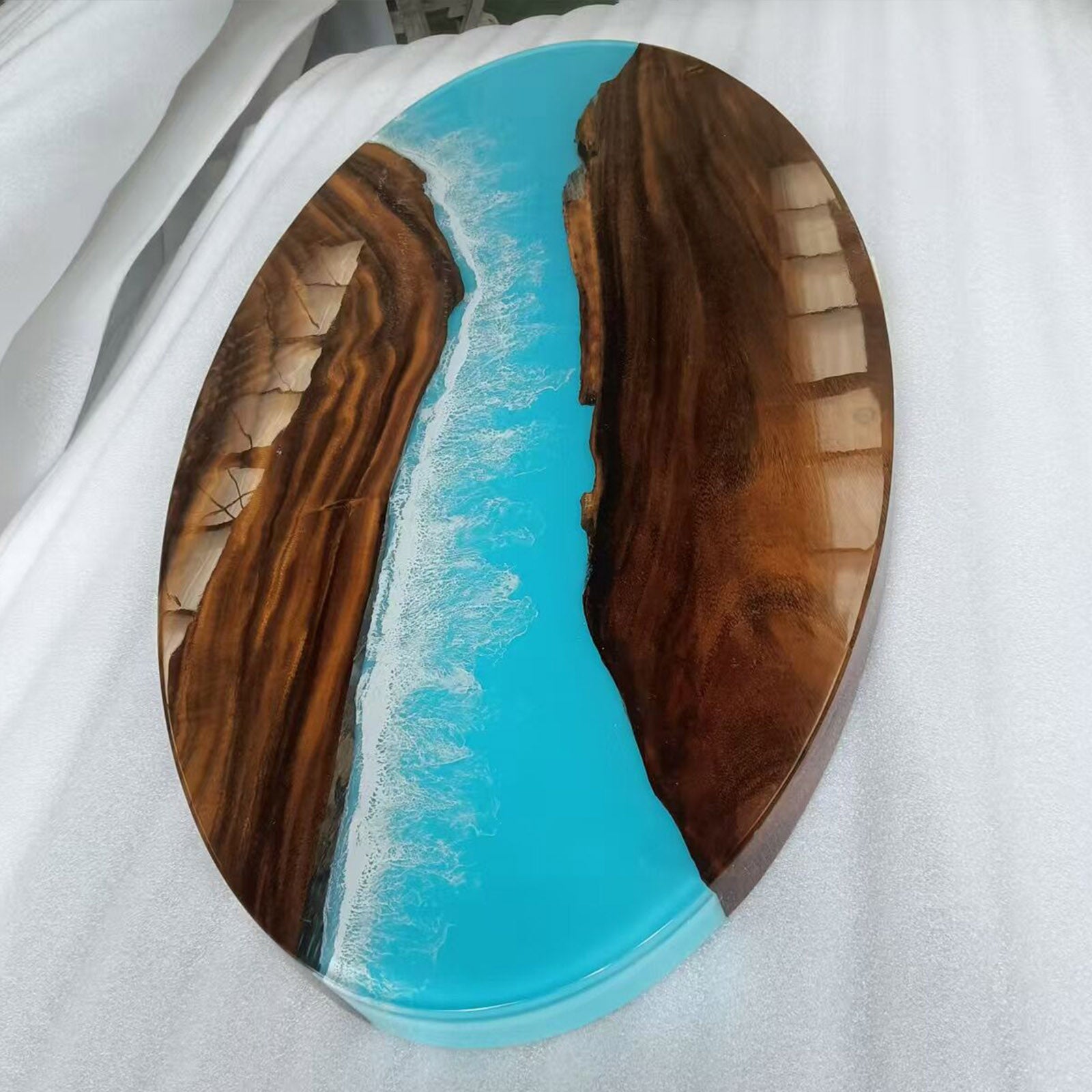 Side view of handcrafted oval walnut coffee table with Ocean Serenity resin river, showing smooth edges and elegant design.