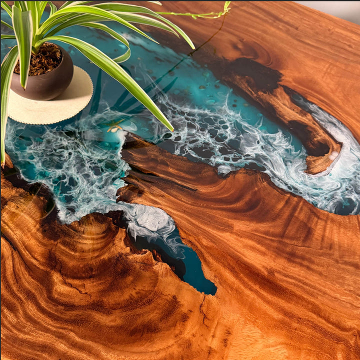 Artistic blend of organic live edge walnut and deep turquoise epoxy, capturing the raw essence of a coastal shoreline in the CRT-272 custom resin table design.