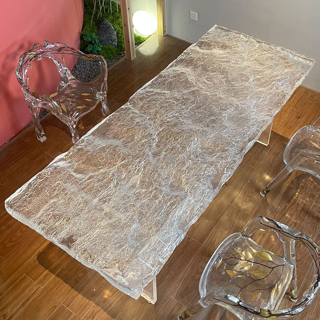 A modern resin dining table with a textured, glass - like surface and clear resin legs.