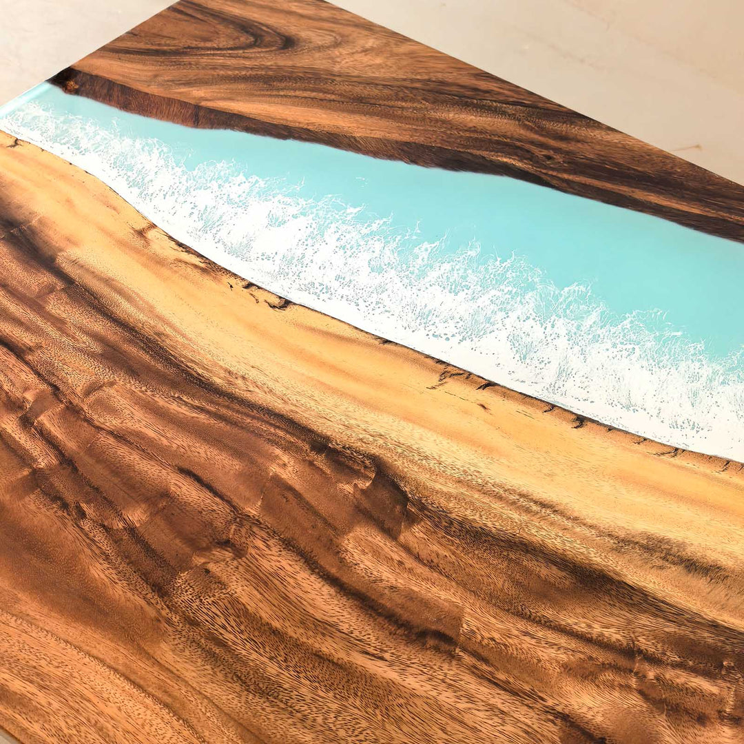 Detailed close-up of blue resin and white foam "sea wave" epoxy design on a solid walnut dining table.