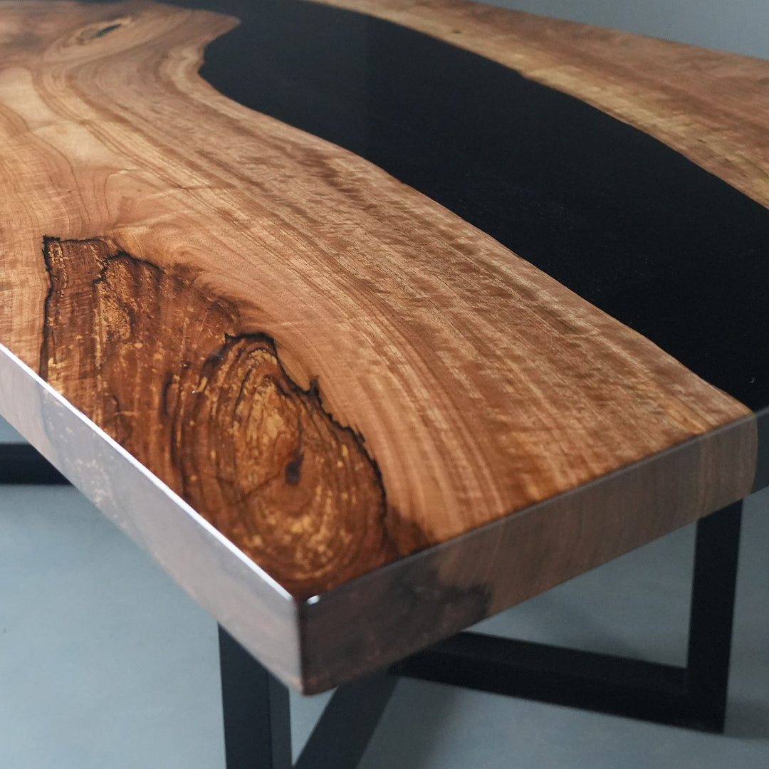 Contemporary black epoxy river dining table showcasing natural wood texture and craftsmanship
