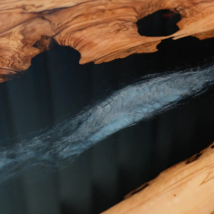 Black epoxy resin river table with contrasting amber olive wood sections