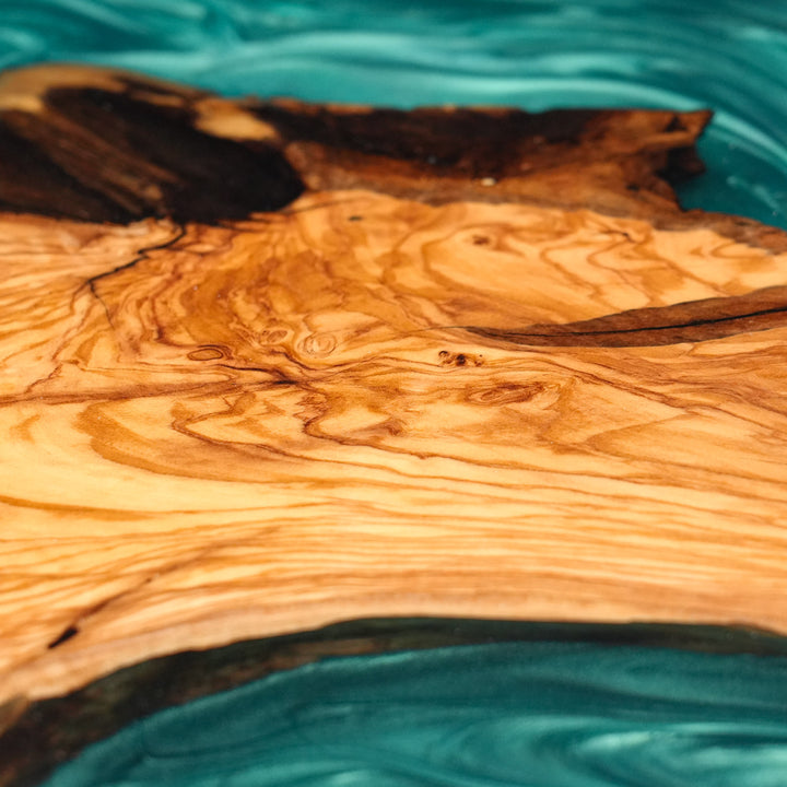 Biophilic design dining furniture featuring teal resin and sustainable raw timber.