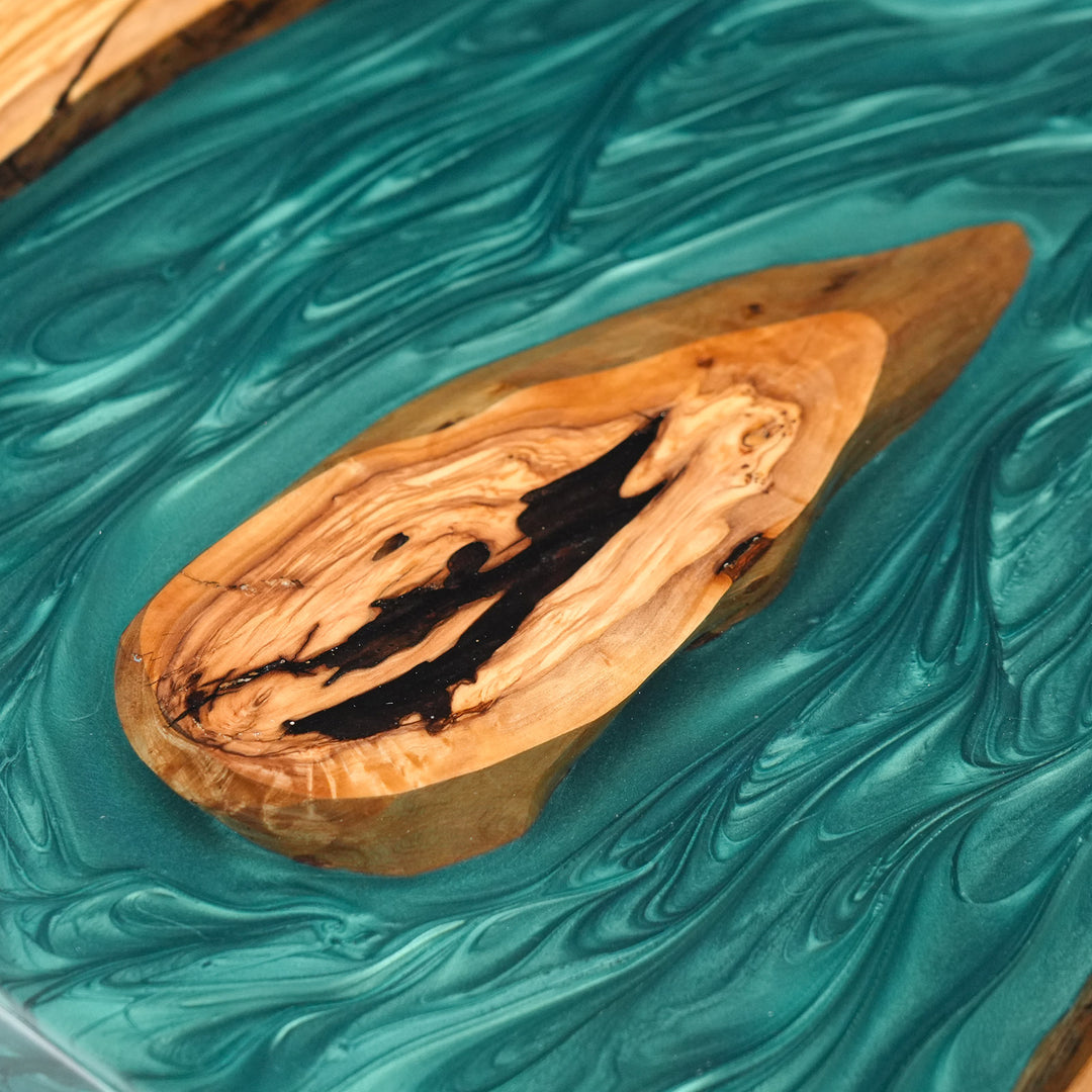 Close-up of crystal clear teal resin waves in a premium live edge wood slab.