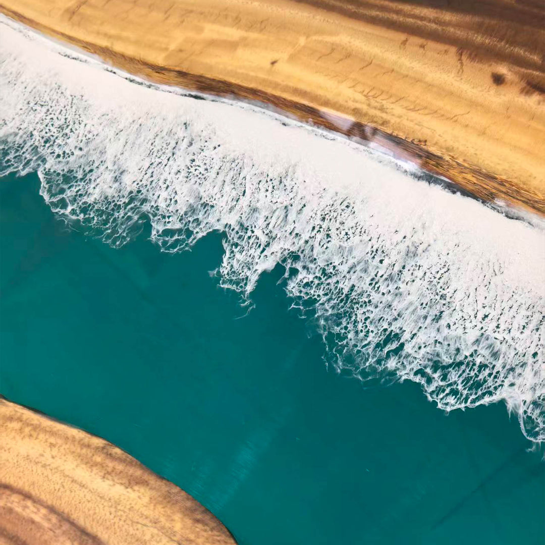 Artisan-made walnut dining table featuring a captivating blue-green resin "river" and white foam.