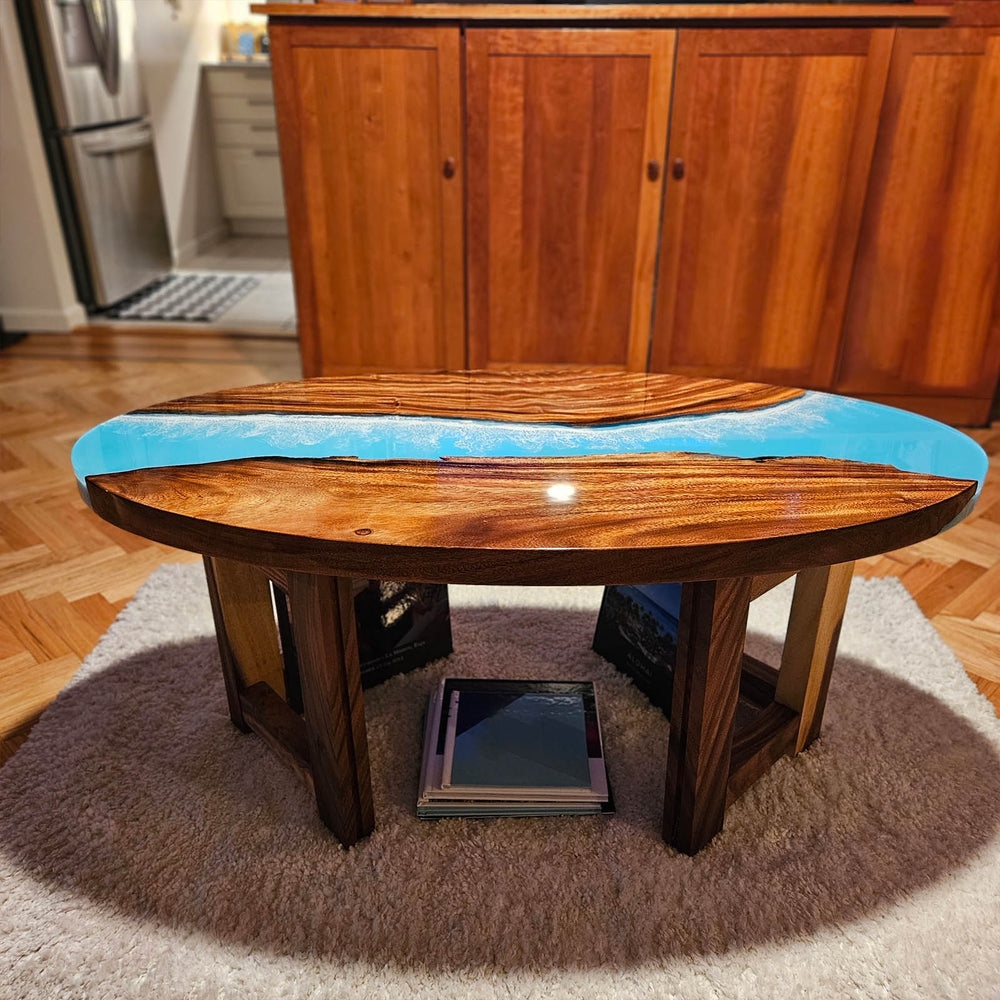 Oval walnut epoxy river table featuring aqua ocean resin design