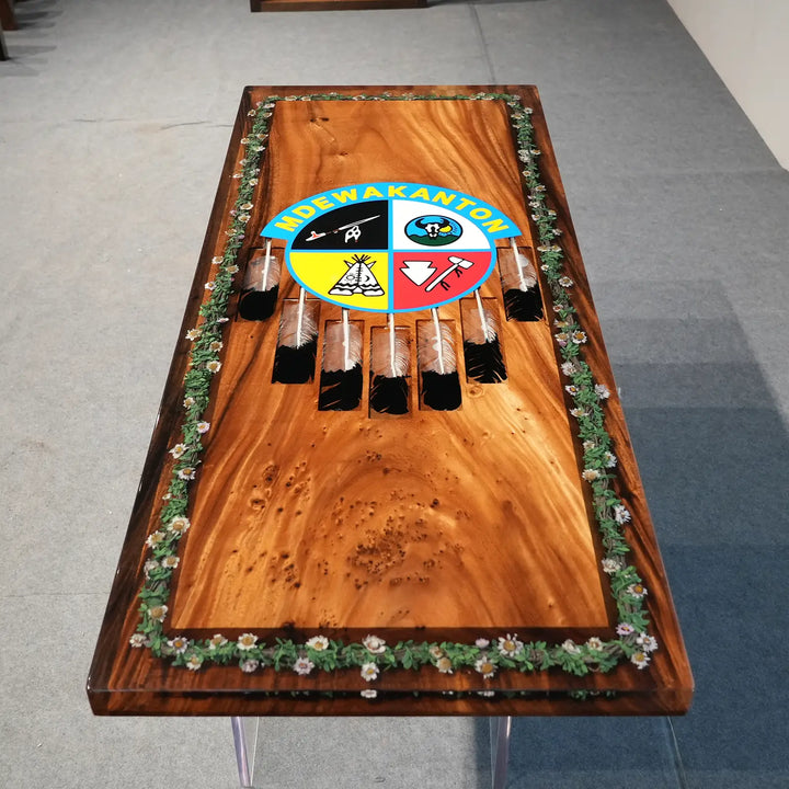 Rustic epoxy resin dining table with colorful central emblem and feather decorations