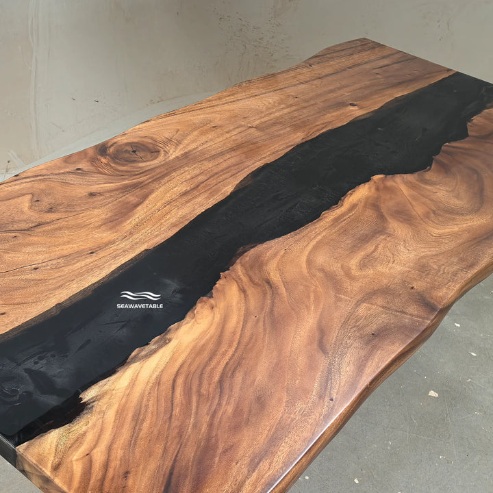 SeawaveTable-A live-edge wooden table with a rich brown wood grain and a glossy black resin river running down the center, featuring a visible 'SEAVAVETABLE' logo on the wood.