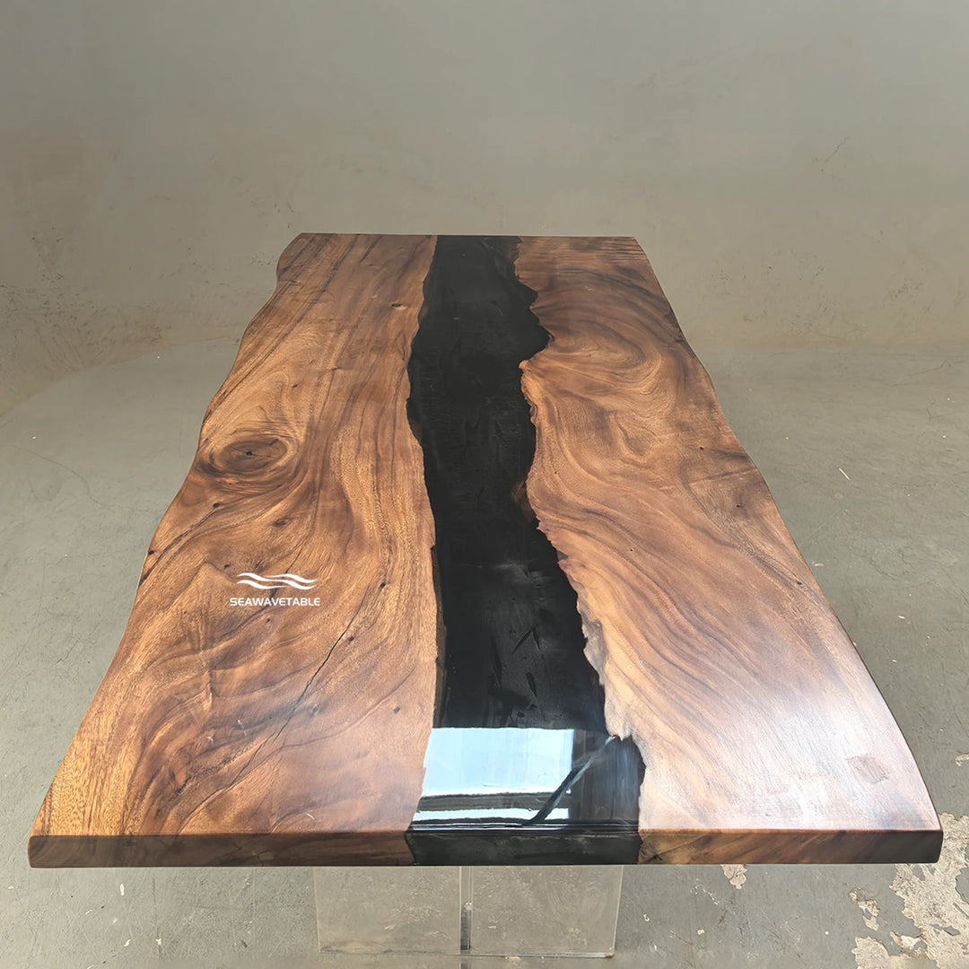 SeawaveTable-A live-edge wooden table with a rich brown wood grain and a glossy black resin river running down the center, supported by clear acrylic blocks on a concrete floor.