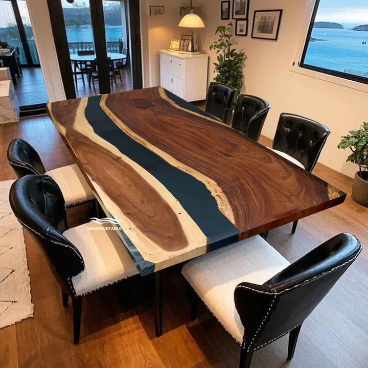 Seawavetable-Dining room with a large wooden table featuring a blue resin inlay, surrounded by black chairs.