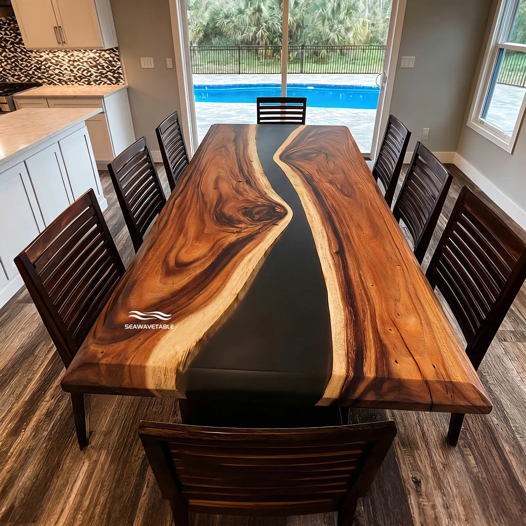 A large live-edge walnut epoxy dining table with a glossy black resin river flowing through the center, surrounded by dark wood chairs in a bright modern dining room with large windows and natural light - SeawaveTable