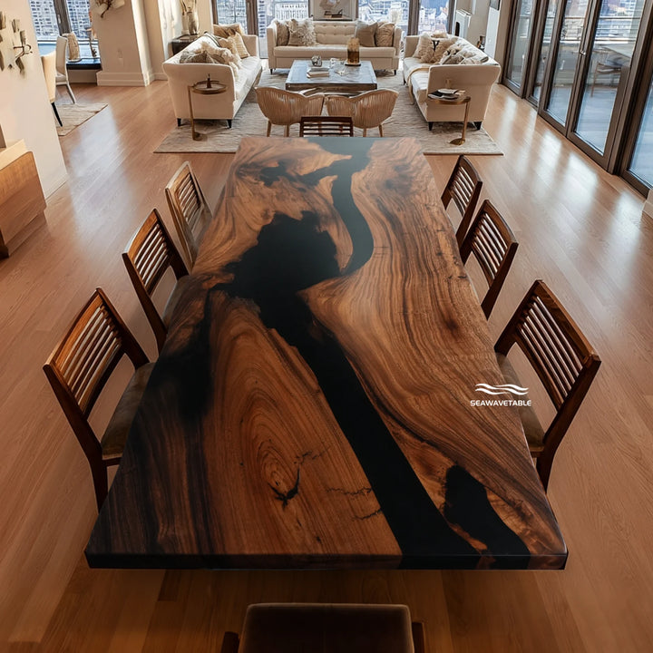 A handcrafted wood dining table made from walnut with a striking black epoxy river channel, positioned in a modern open-concept living room with large windows and wooden seating - SeawaveTable