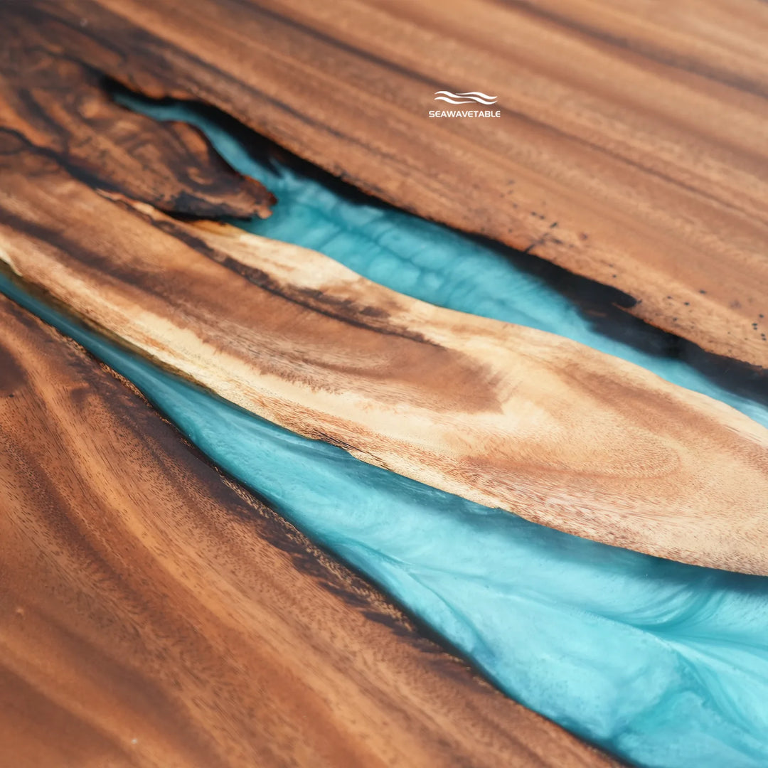 Close-up of a wooden surface with a carved turquoise river design running through it, featuring natural wood grain and a small visible SCANWORTHAM logo near the top center.