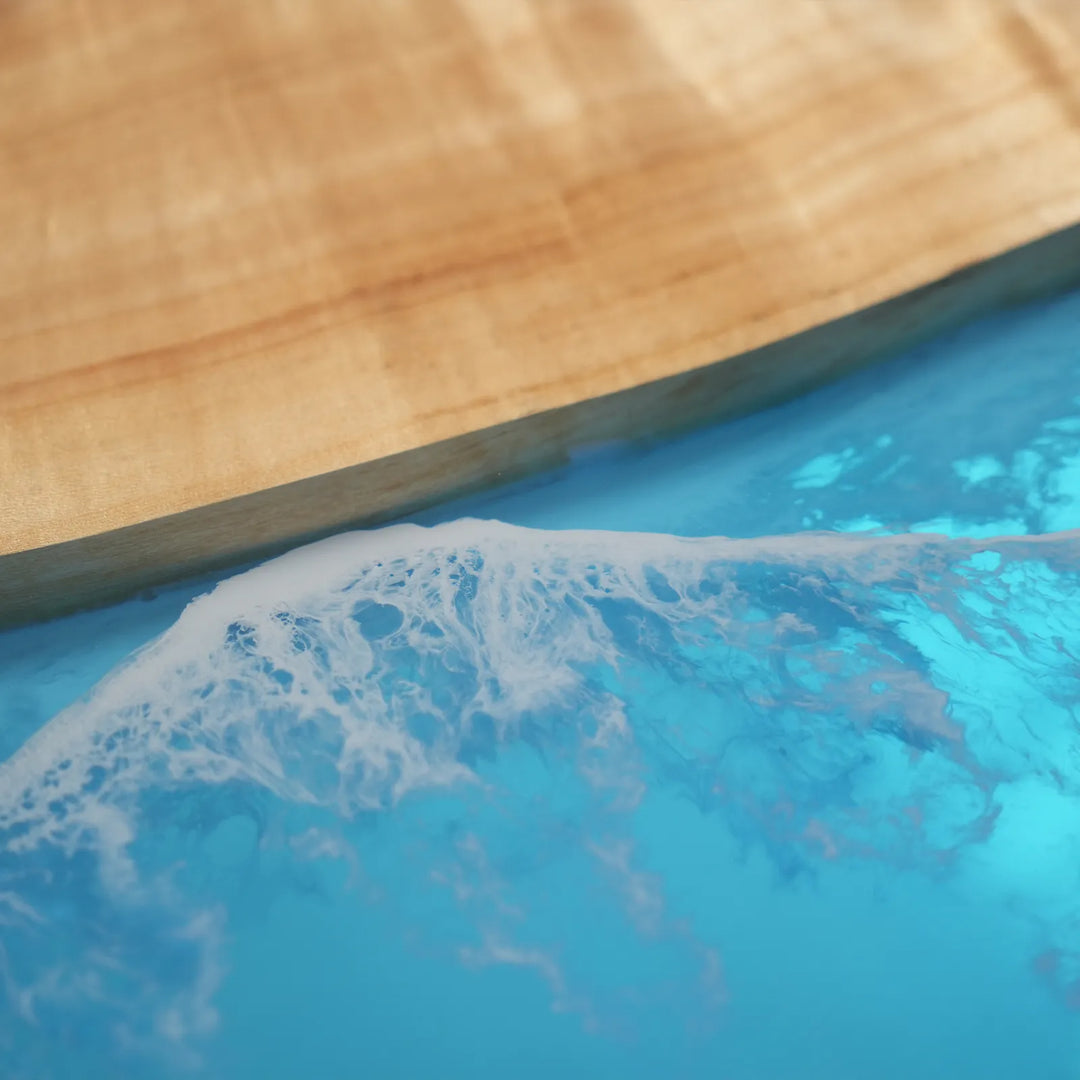 Close-up detail of an epoxy table showing the vibrant blue ocean channel flowing through the natural poplar grain with smooth polished finish - SeawaveTable