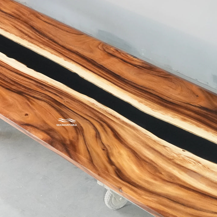 Surface detail of a custom epoxy table capturing the striking contrast between the warm walnut wood and the deep black resin river - SeawaveTable