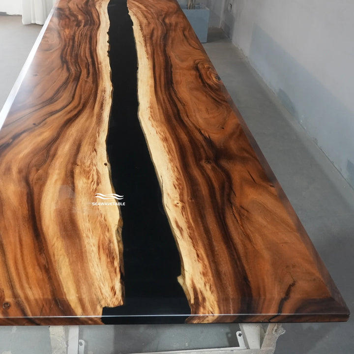 Close-up detail of an epoxy table showing the dark resin river flowing through the rich walnut grain with smooth polished finish - SeawaveTable