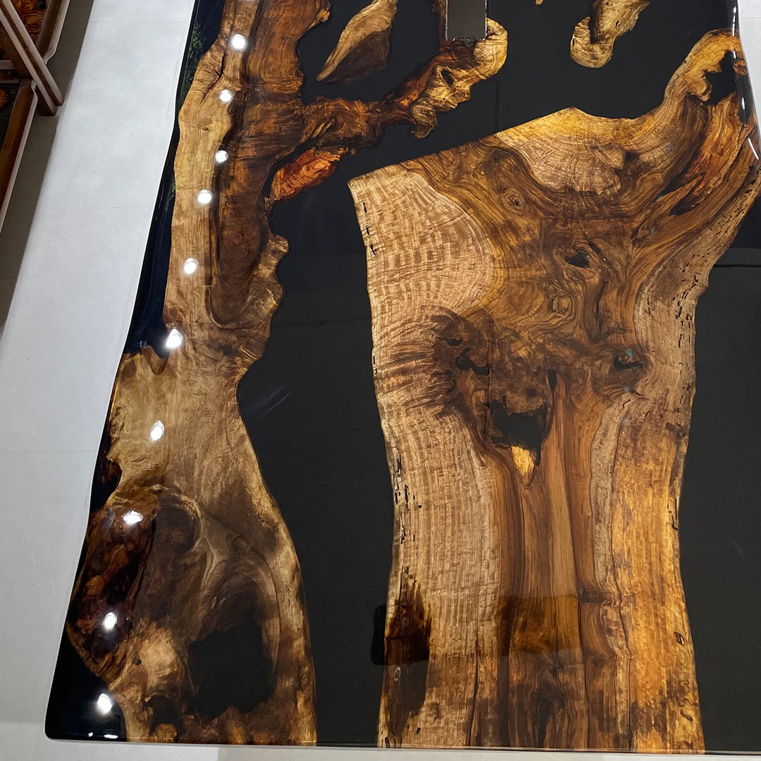 Seawavetable-A live-edge wooden tabletop with dramatic swirling natural wood grain in warm brown and golden tones, filled with glossy black resin and accented by a row of small integrated lights along the left edge.