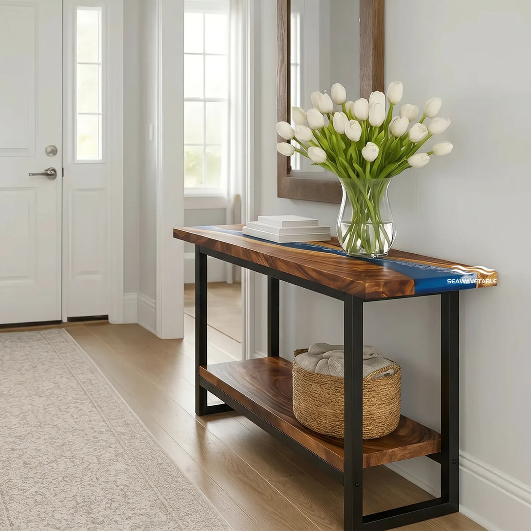 A walnut epoxy dual-layer console table with a flowing blue resin river on the top surface and a lower wooden shelf, placed in a bright entryway with a mirror and decorative accents - SeawaveTable