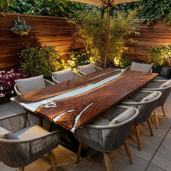 A handcrafted resin table with live-edge black walnut and white resin river, positioned on a spacious tiled patio overlooking a garden, perfect for alfresco dining and gatherings - SeawaveTable