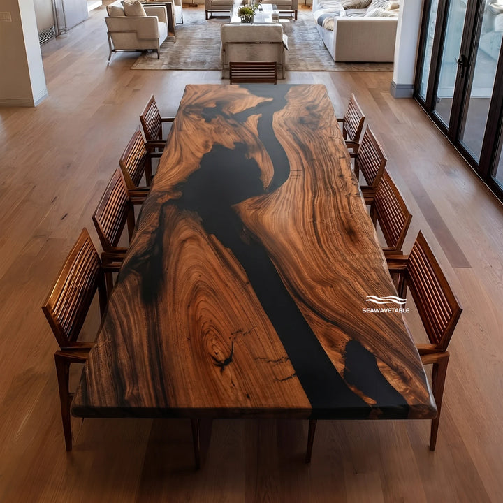 A long live-edge walnut dining table with a dramatic black resin river running through rich brown wood grain, surrounded by matching wooden chairs in a modern open-plan living space with natural light - SeawaveTable