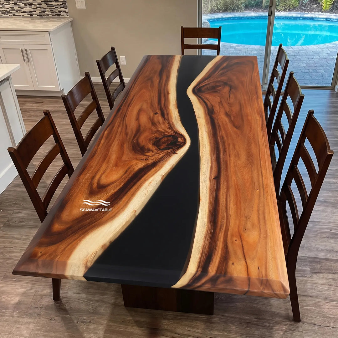A handcrafted resin table with live-edge walnut and deep black resin channel, positioned in an elegant modern dining room with stylish dark chairs and soft natural light from nearby windows - SeawaveTable