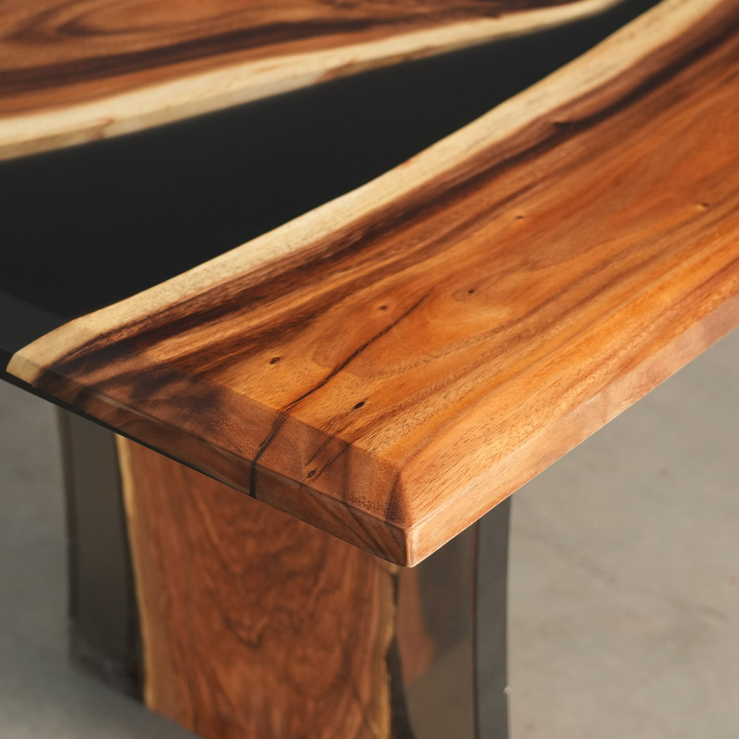 Close-up detail of an epoxy table showing the glossy black river channel cutting through the rich walnut grain with smooth reflective finish - SeawaveTable
