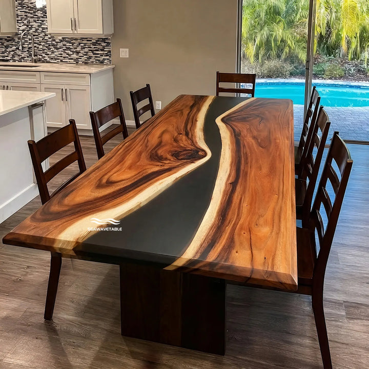 Custom solid wood dining table featuring a rich walnut slab with flowing black resin river, placed in a contemporary dining space with dark wooden seating and warm ambient lighting - SeawaveTable