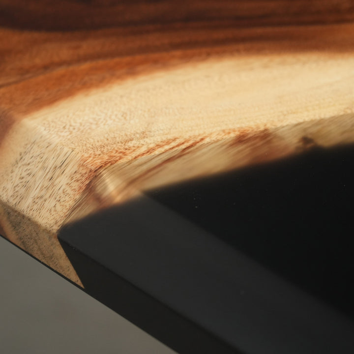 Close-up of a beveled-edge dining table showing the organic edge contour where the walnut meets the glossy black resin - SeawaveTable