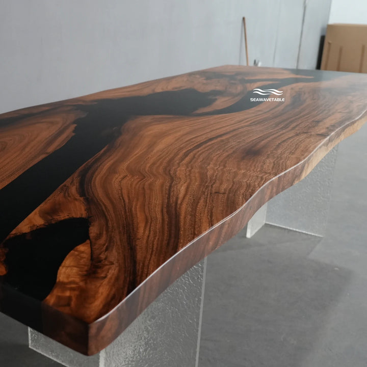 Surface detail of a custom epoxy table capturing the striking contrast between the warm walnut wood and the deep black glossy resin river - SeawaveTable