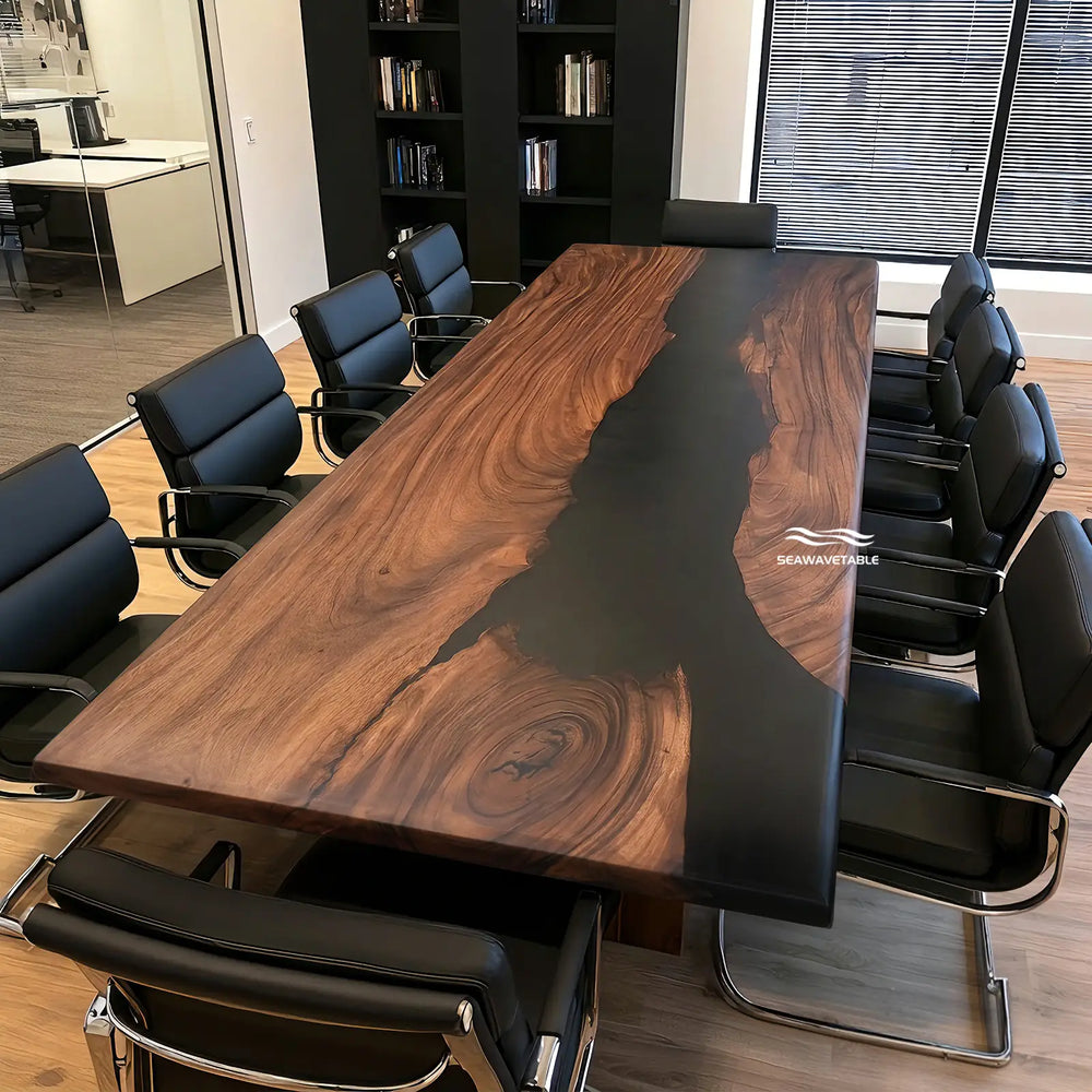A large rectangular conference table with a rich dark wood grain and a glossy black resin center channel, surrounded by black office chairs in a modern office setting. A watermark logo for 'SEARAWOOL' is visible on the right side of the tabletop.