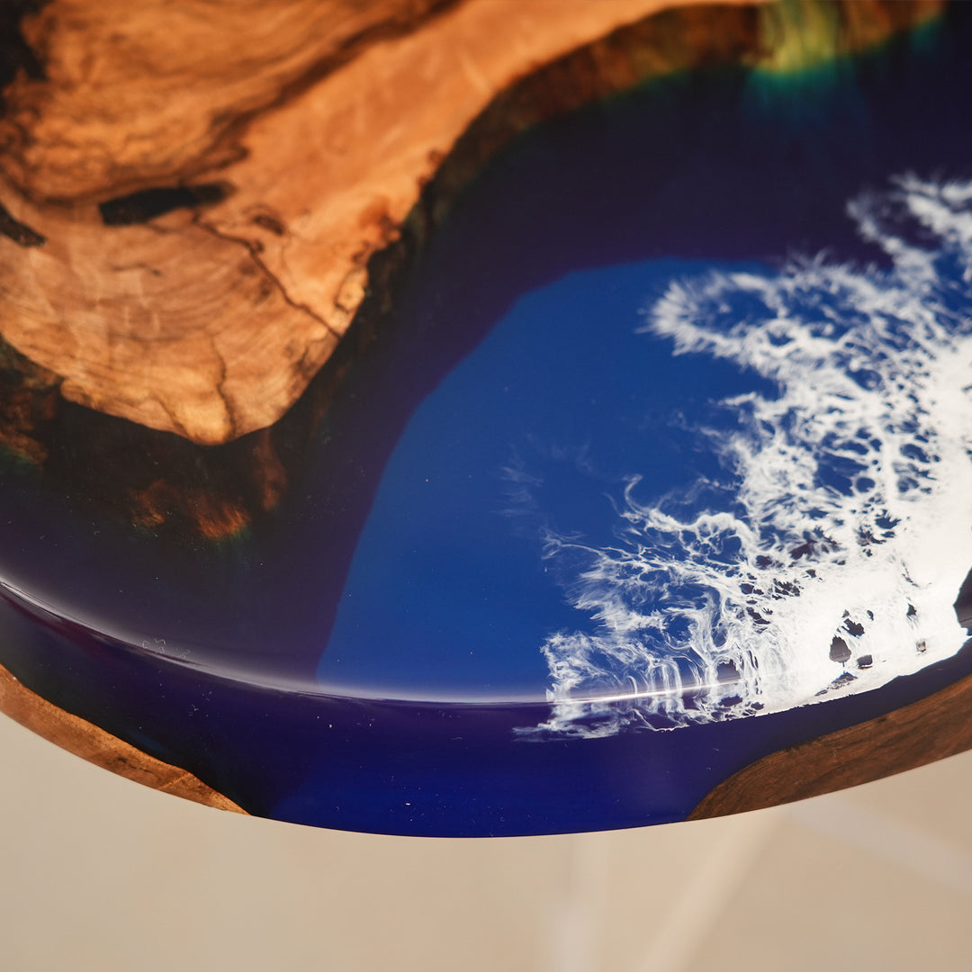 Seawavetable
Modern oval epoxy dining table with swirling blue and white wave resin and natural hardwood set against a cityscape window view.