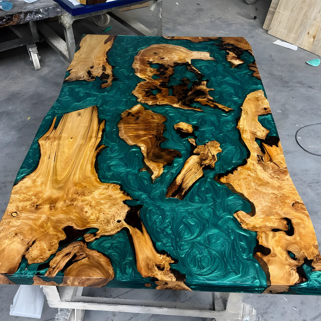 Seawavetable-A rectangular live-edge wooden table with a glossy teal resin finish and natural burl wood sections, photographed in a workshop setting.