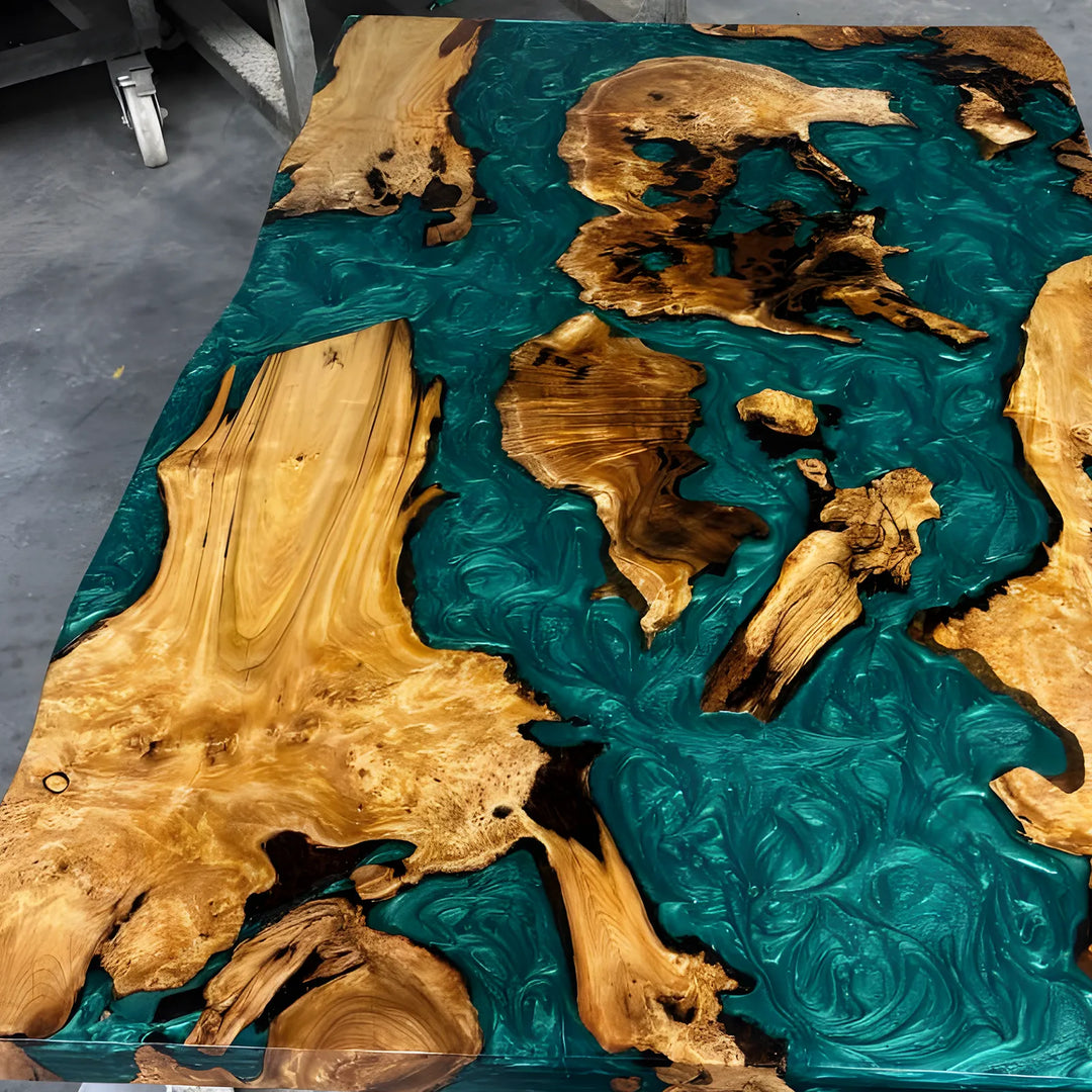 Seawavetable-A rectangular live-edge wooden table featuring swirling teal resin channels and natural wood continents, photographed from above on a gray floor.