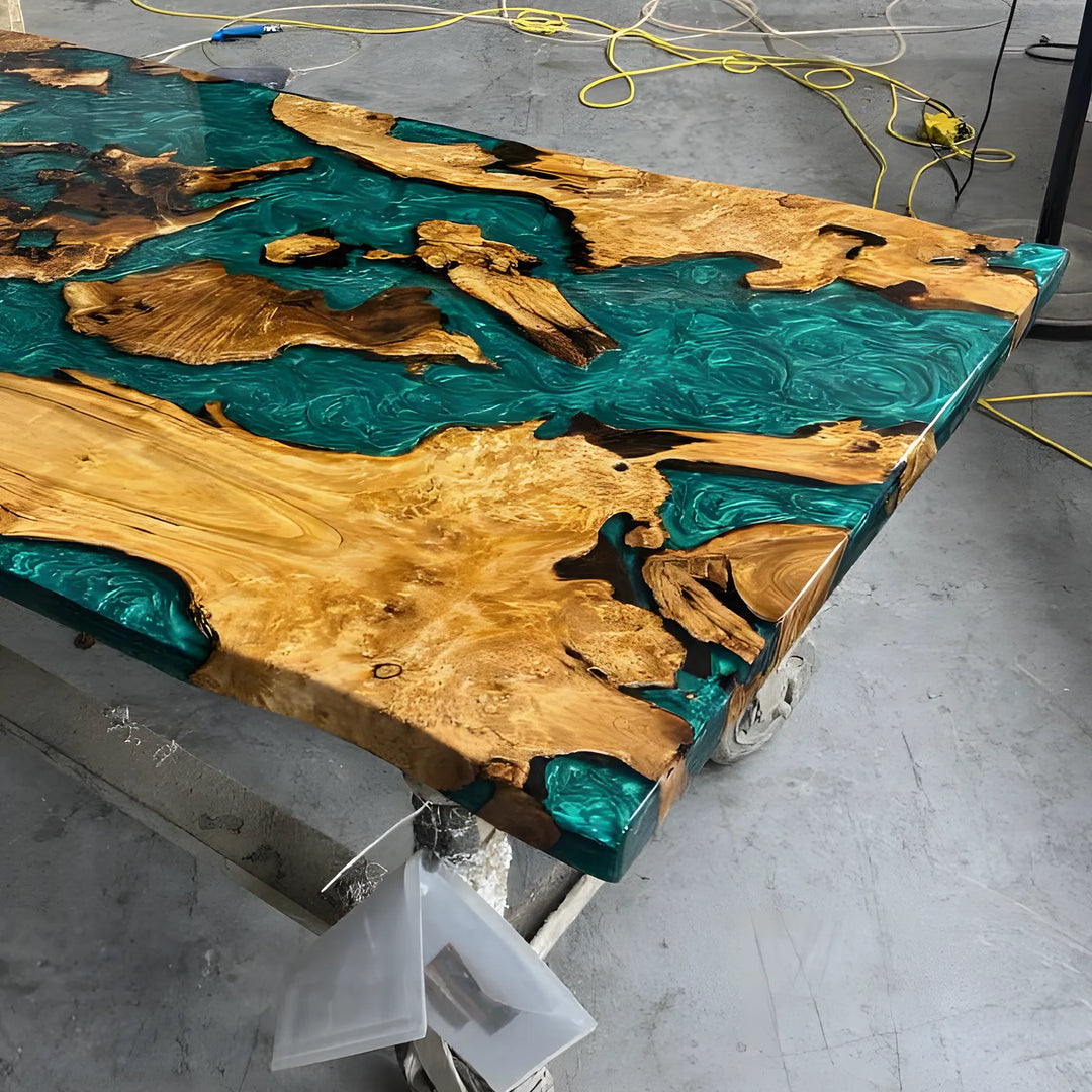 Seawavetable-A spacious live-edge wood table featuring a smooth natural finish and vibrant teal blue epoxy channels, photographed in a woodworking studio.