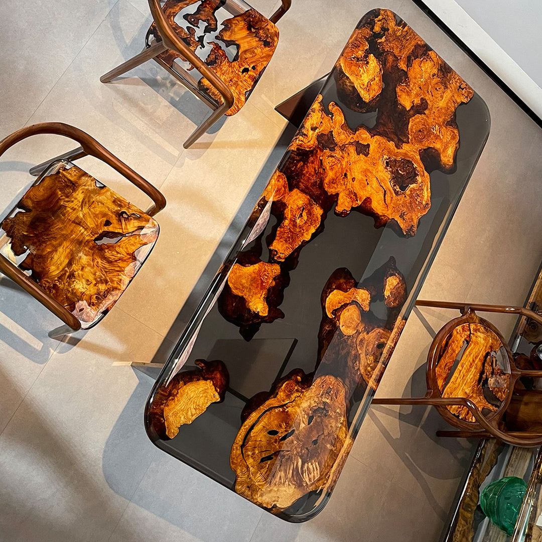 A golden camphor wood resin table with a striking, organic-patterned surface, accompanied by matching chairs.