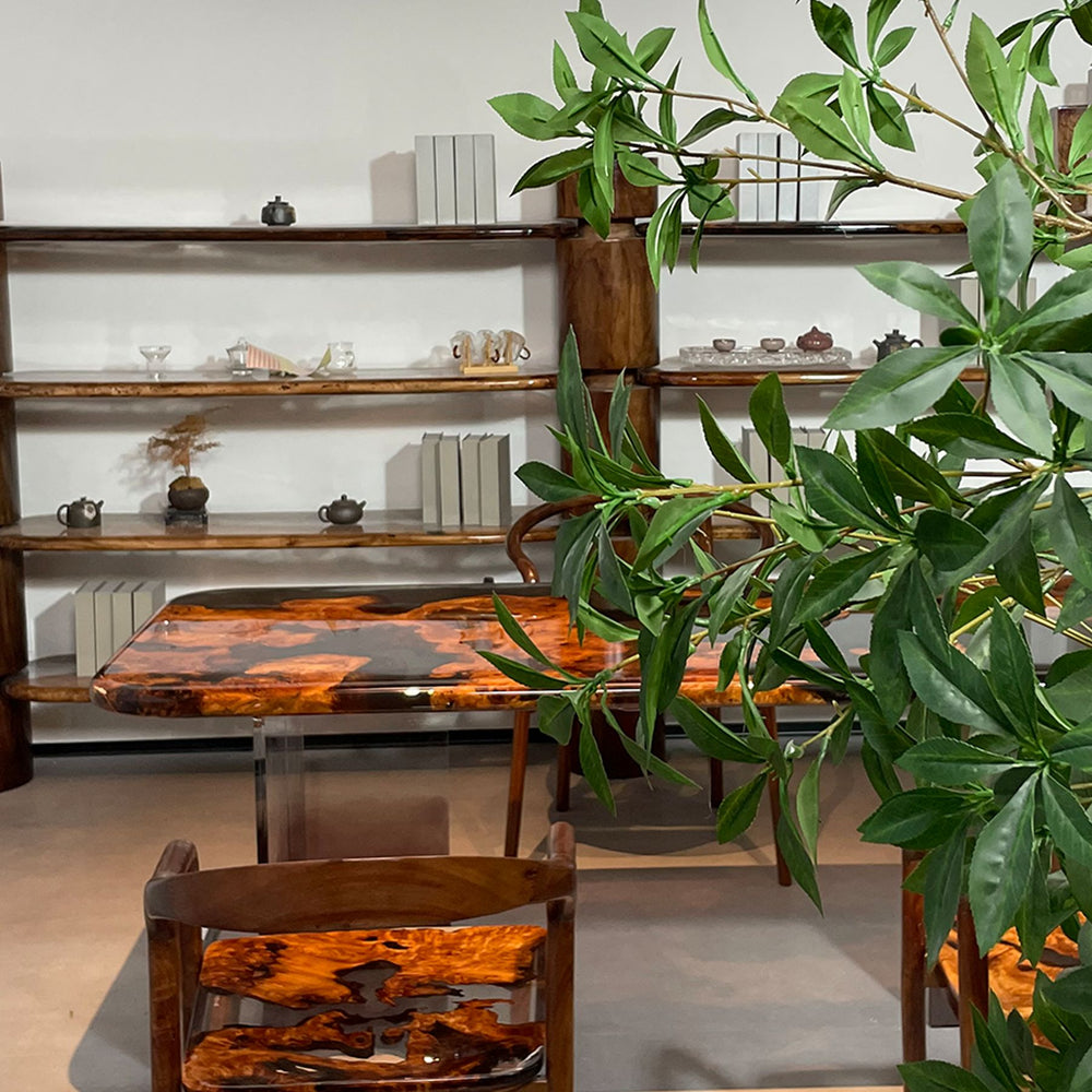 A resin - finished wooden table with a unique pattern, surrounded by matching chairs, set against a backdrop of shelves with decorative items.