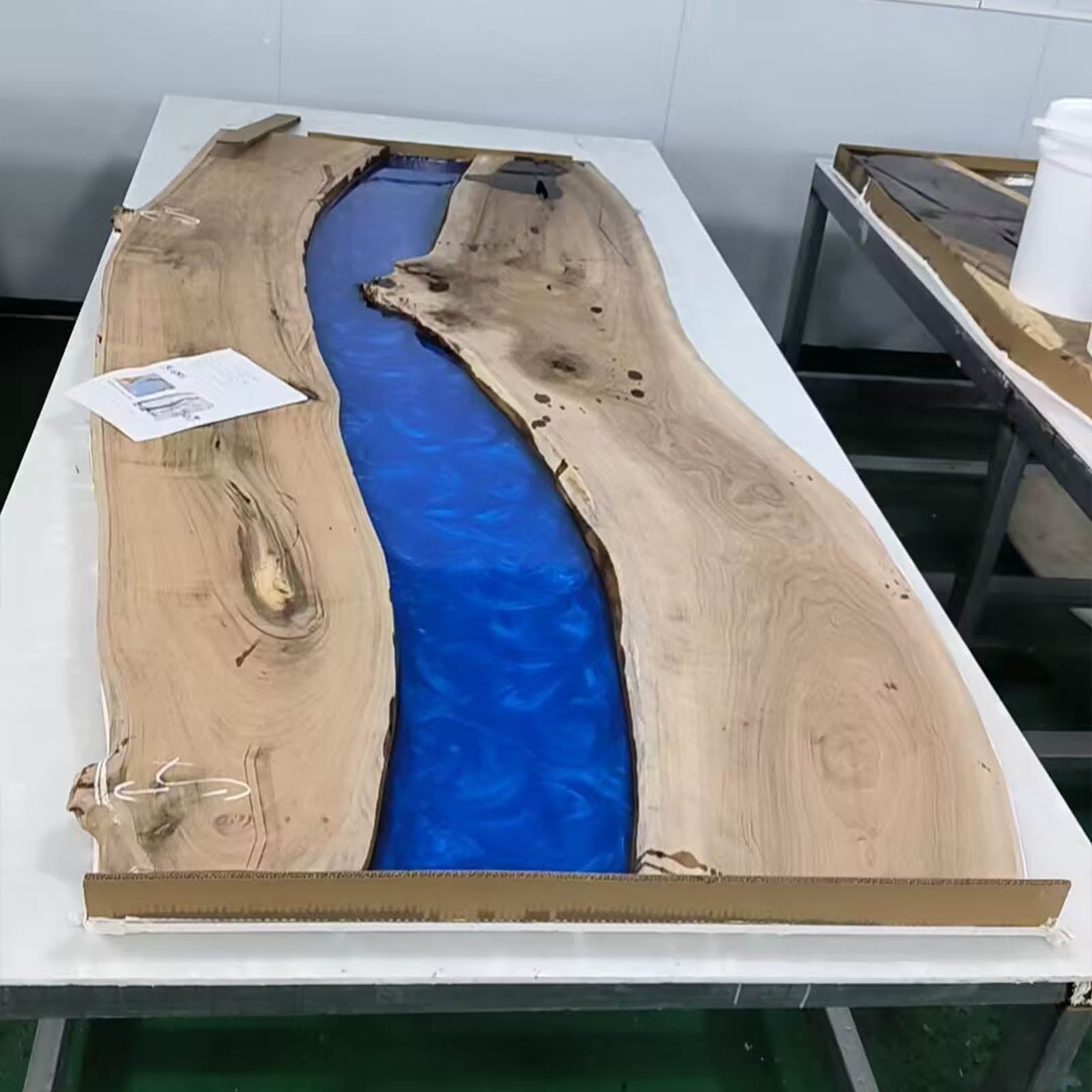 Handcrafted black walnut dining table with live edge design, swirling ocean blue epoxy river, and ambient LED lighting.