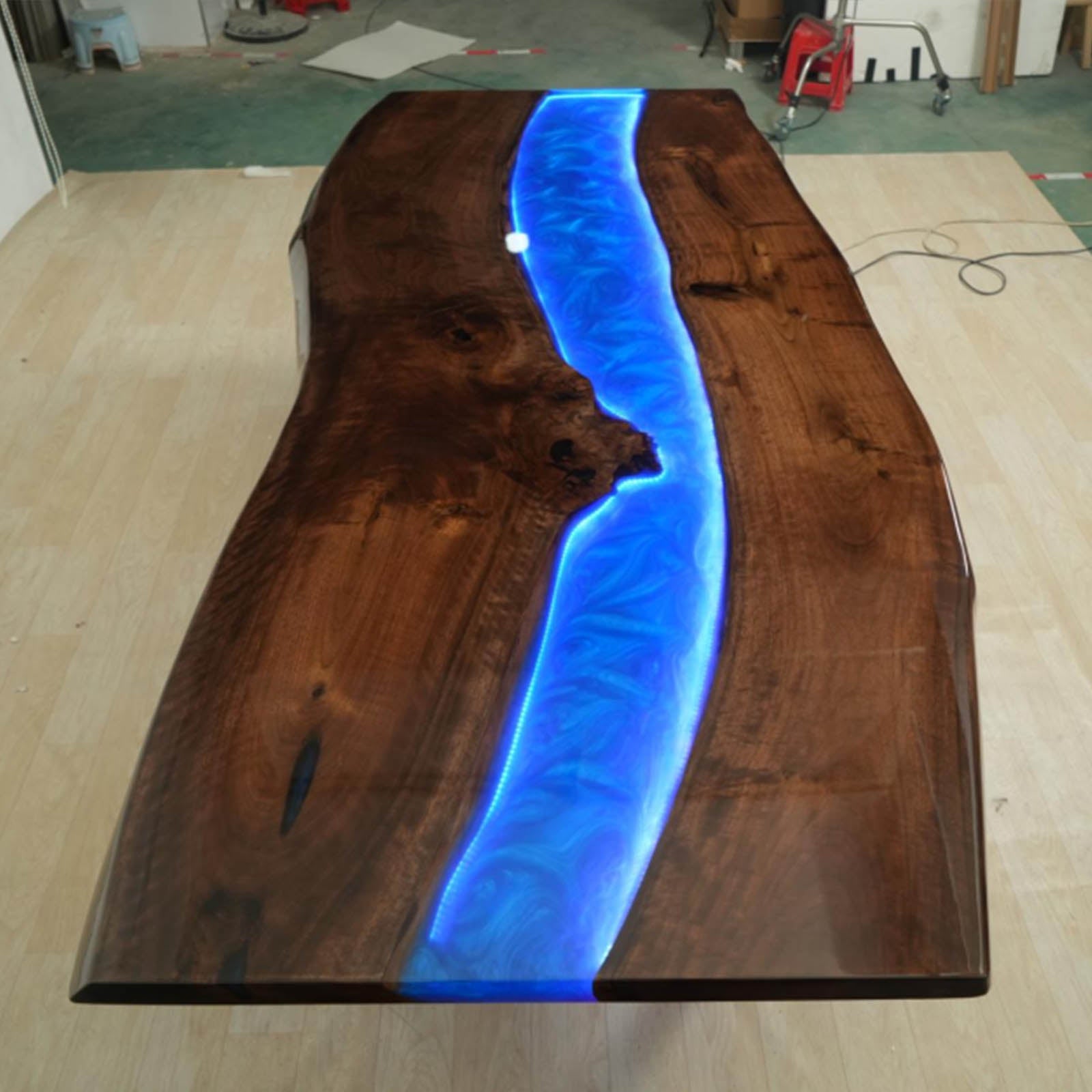 Detail view of LED lighting integrated into a swirling ocean blue epoxy river on a handcrafted black walnut live edge table.